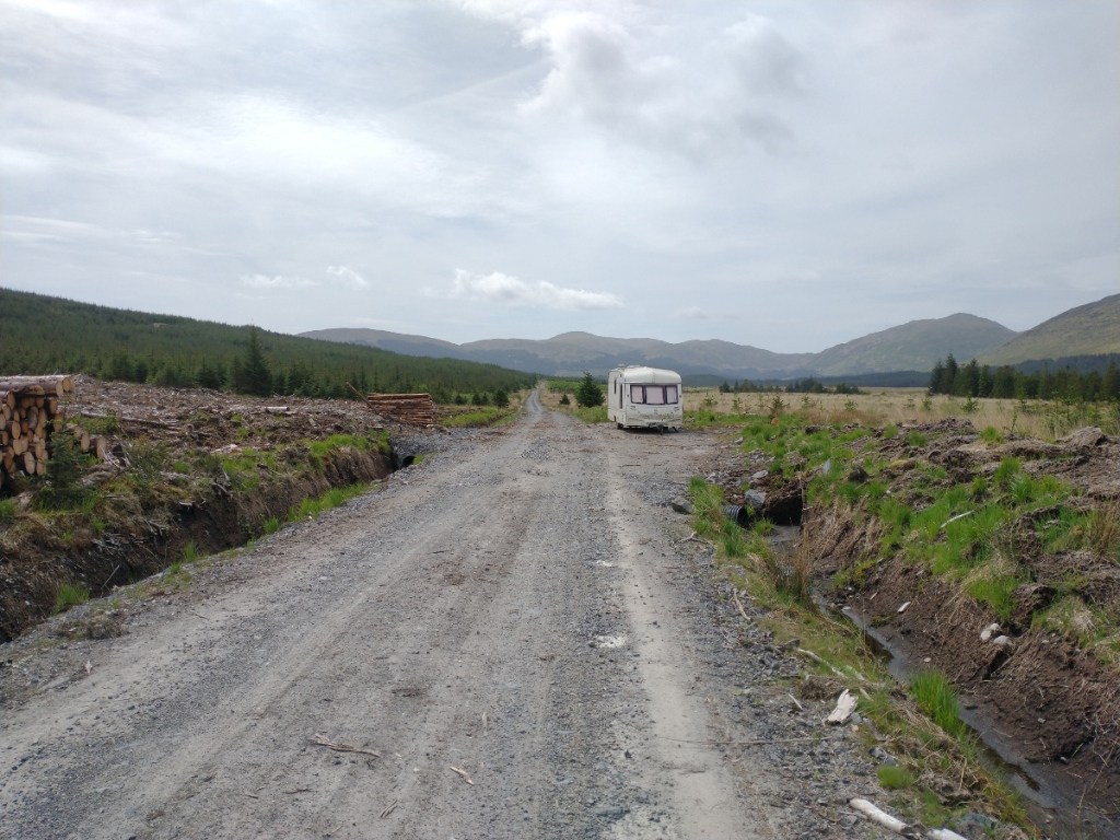 view down the glen with a forestry worker's caravan parked beside the track